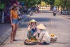 Street sellers sell fruit in traditional hats to tourists
